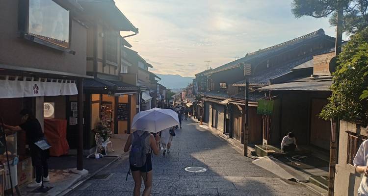 Vue de rue de boutiques japonaises traditionnelles avec des gens et un coucher de soleil.
