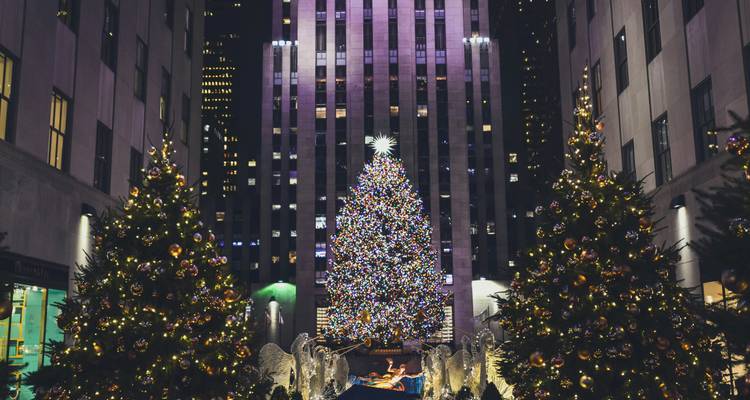 Sapin de Noël et anges devant un gratte-ciel illuminé.