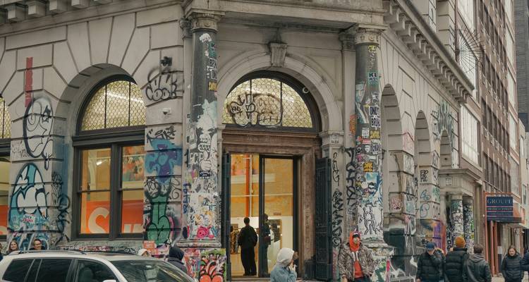 Extérieur de bâtiment avec graffitis et personnes.