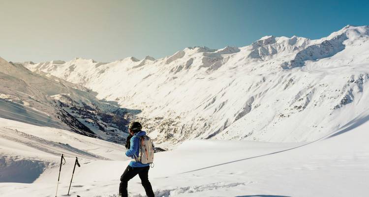 Personne faisant du ski sur les pentes enneigées de la montagne par une journée claire.