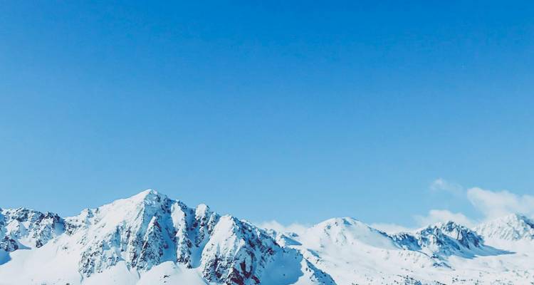 Des montagnes enneigées sous un ciel bleu clair.