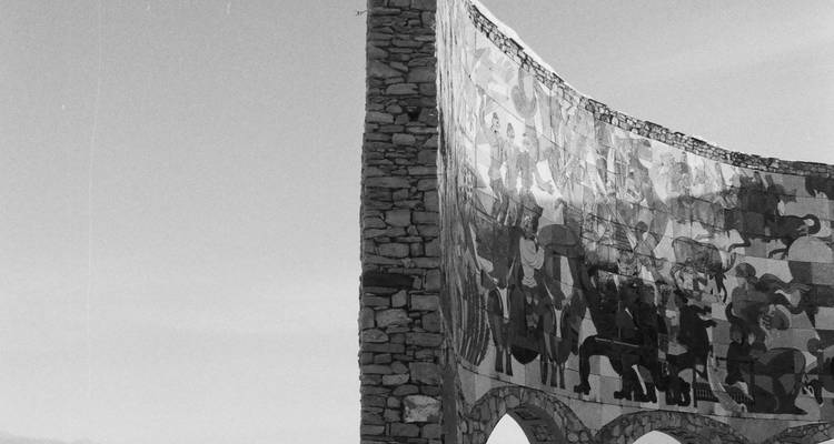 Monument avec œuvre d'art en relief sur un arrière-plan de montagne.