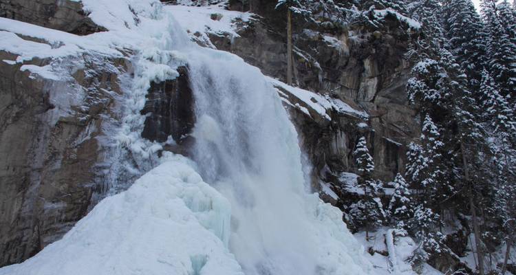 Frozen waterfall with ice layers in a forest.