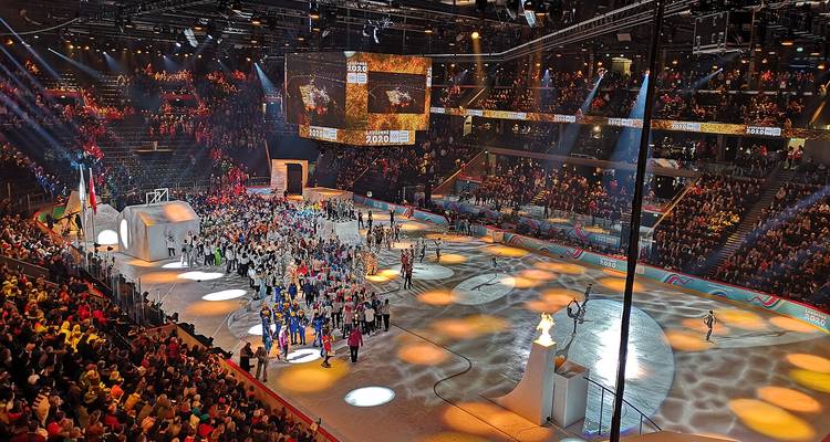 Indoor event with a large crowd and performances on ice.