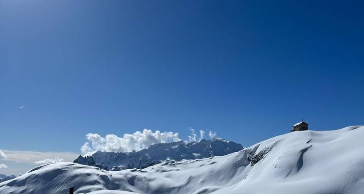 Paysage enneigé avec une maison solitaire sur une colline.
