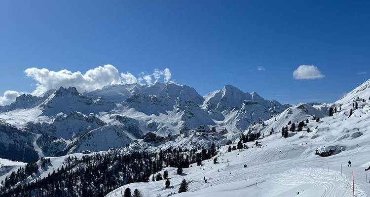 Vue panoramique de montagnes enneigées avec un ciel bleu dégagé.