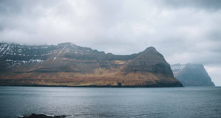 Vue sur la montagne et la mer sous un ciel nuageux.