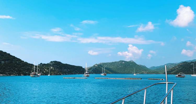 Blick auf Yachten, die in einer blauen Bucht vor Anker liegen, umgeben von Hügeln.