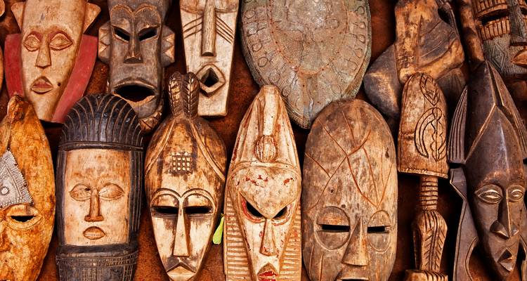 Masques traditionnels en bois disposés dans un cadre de marché.