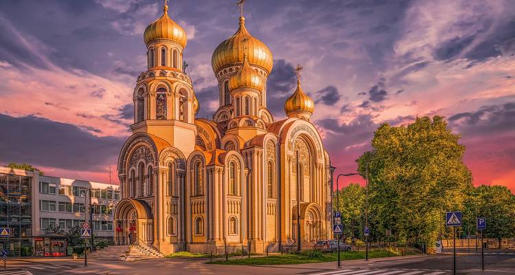 Église ornée avec des dômes dorés au coucher du soleil.