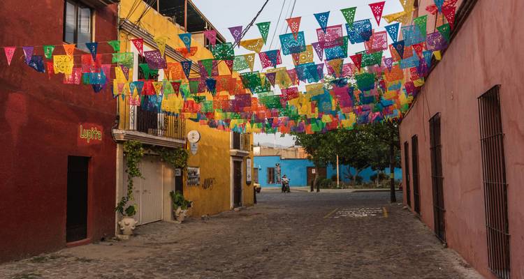 Une rue colorée avec des drapeaux suspendus au-dessus et des bâtiments vibrants.