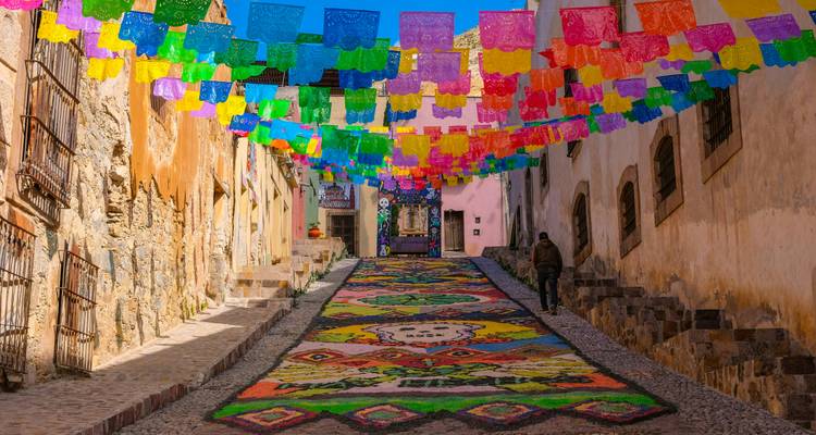 Bunte Dekorationen und Kunst an einer abschüssigen Straße in Mexiko.