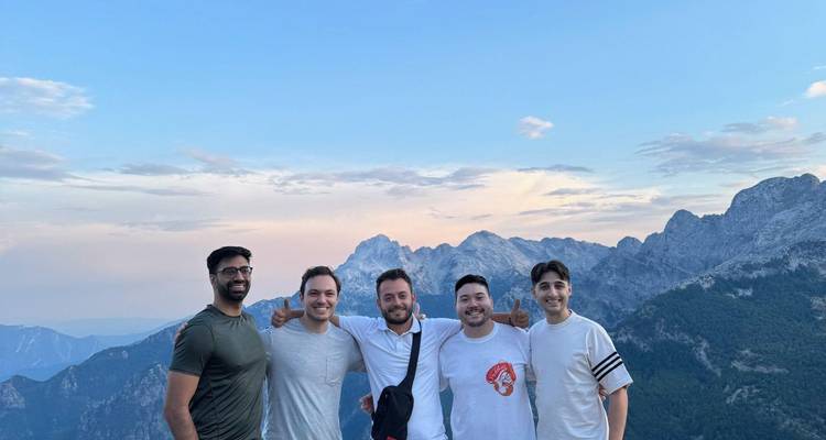 Grupo de personas posando con montañas al fondo.
