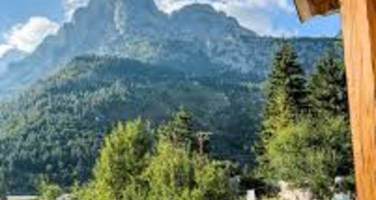 Vista de montaña con una cabaña de madera en primer plano.