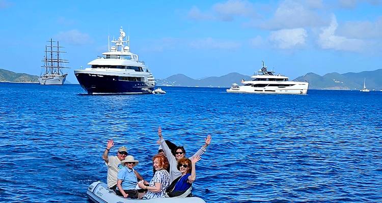 Family on a small boat in front of large yachts in the sea.