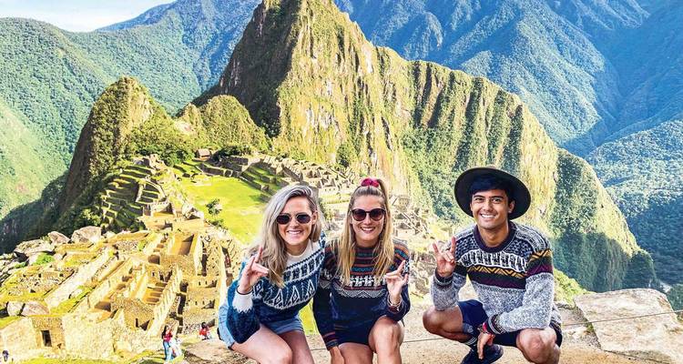 Three travelers posing with scenic Machu Picchu in the background.