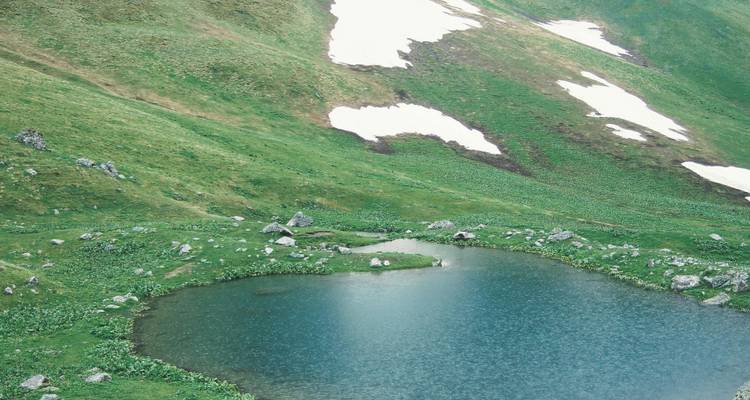 Petit lac entouré de collines herbeuses.