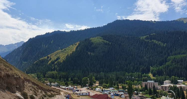 Vue d'un village avec des collines boisées en arrière-plan.