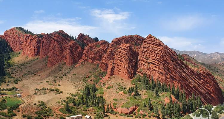 Formations rocheuses rouges spectaculaires dans un paysage accidenté.