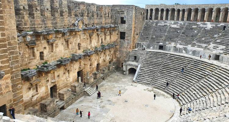 Ancien amphithéâtre romain avec des visiteurs dispersés.