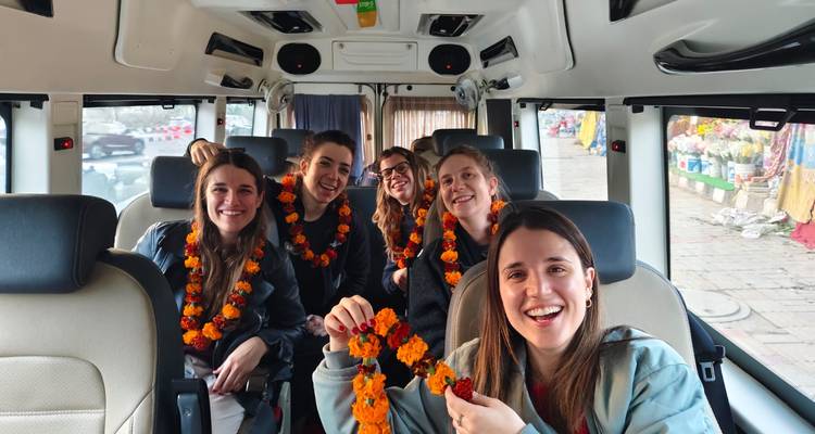 Glimlachende reizigers die goudsbloemslingers dragen zitten in een toeristische minibus.
