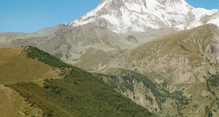 Un paisaje montañoso pintoresco con un pico cubierto de nieve en el fondo.