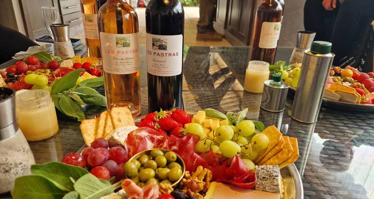 Table avec de la nourriture gastronomique et des vins, incluant des fromages et des fruits.