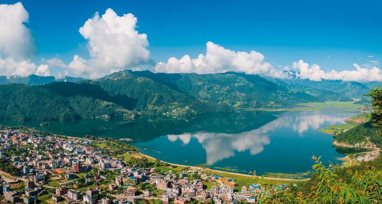 Panoramisch uitzicht op een meer met omliggende heuvels en stad.
