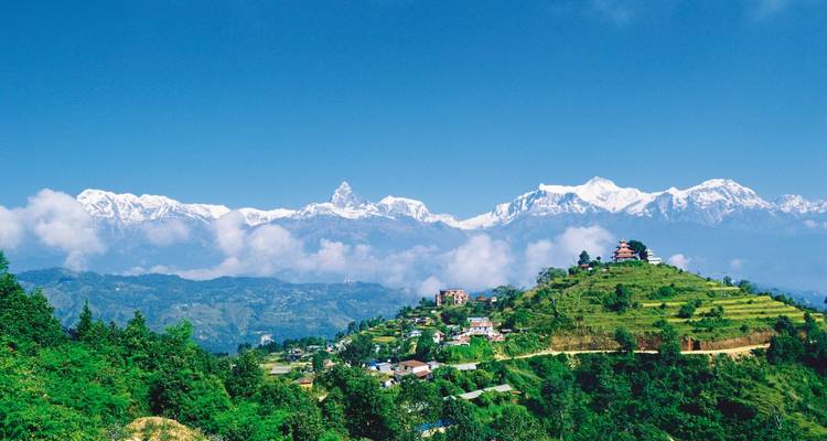 Schilderachtig uitzicht op een weelderige groene heuvel met bergen en een tempel.