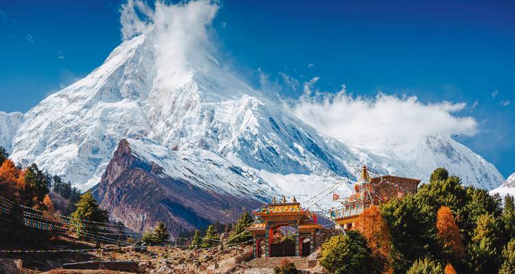 Majestueuze met sneeuw bedekte piek met een levendig klooster.