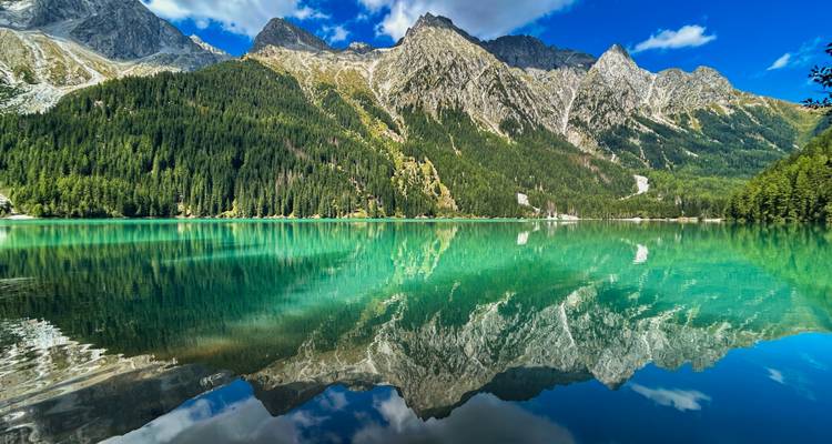 Atemberaubende Bergspiegelung auf einem türkisfarbenen See unter klarem Himmel.