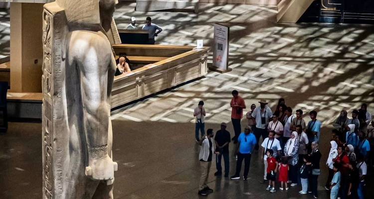 Estatua con una multitud de personas dentro de un edificio moderno.