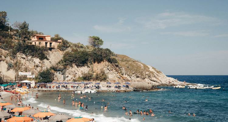 Een druk strand met mensen die zwemmen en zonnebaden.