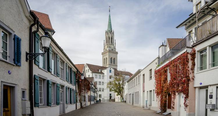 Street view in a historic town with a tower and traditional buildings.