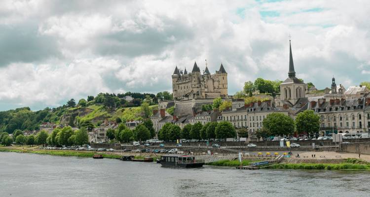 Une ville au bord de la rivière avec un château sur une colline.