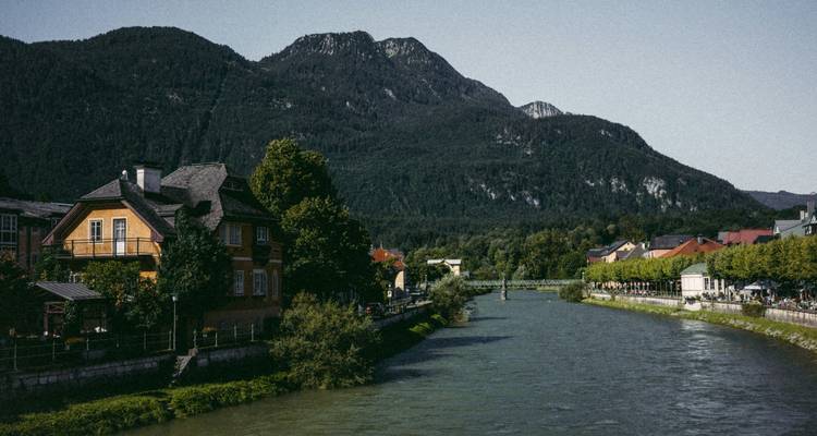 Rivier die door een stad stroomt met een bergachtig decor op de achtergrond.