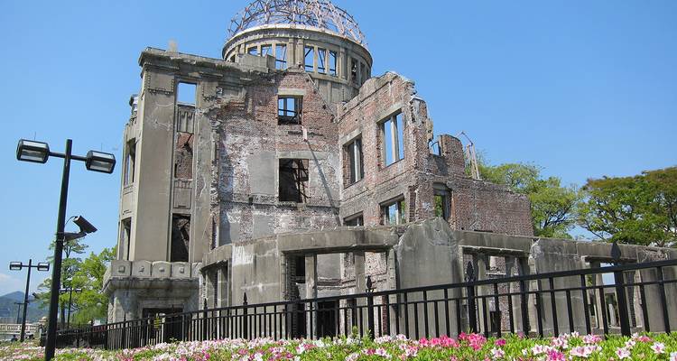 Ruins of historic building with flowers and clear sky.
