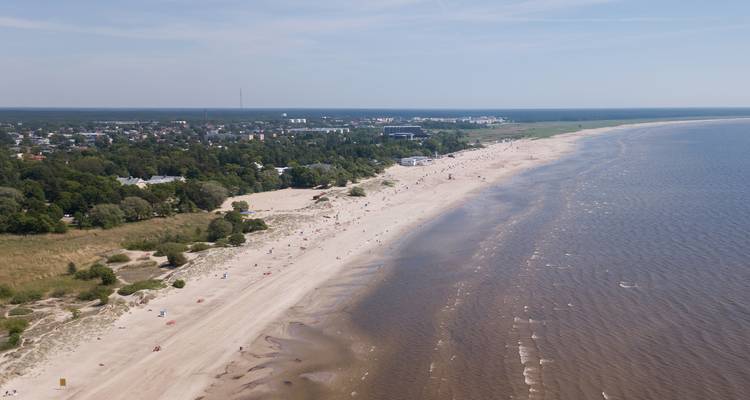 Lang zanderig strand met een paar mensen en een stad in de verte.