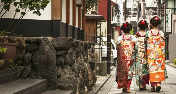 Trois femmes en kimonos marchant dans une rue japonaise traditionnelle.