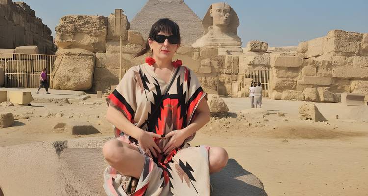 Une personne assise devant le Sphinx et les pyramides de Gizeh.