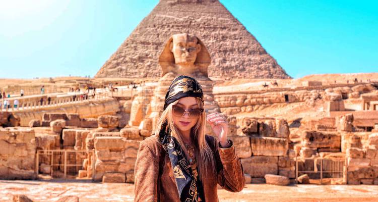 Femme élégante posant devant le Sphinx avec la Grande Pyramide s'élevant en arrière-plan.