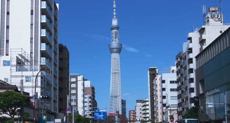 Tokyo Skytree erhebt sich zwischen modernen Stadtgebäuden unter einem klaren blauen Himmel.
