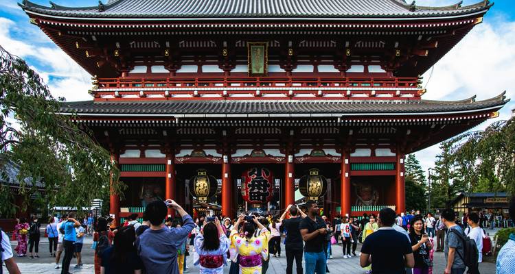 Menschenmengen versammeln sich am Eingangstor des Senso-ji-Tempels in Tokio, umrahmt von lebendigen roten Säulen und Laternen.