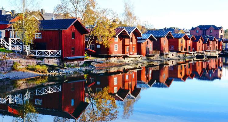 Rustic wooden houses reflected in the water in Finland.