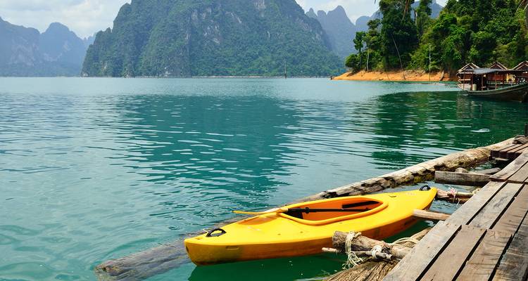 Kayak amarillo flotando en un lago sereno rodeado de montañas.