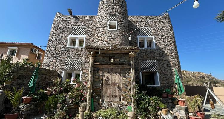 Facade of a traditional building with plants and clear blue sky.