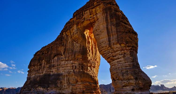 Natural rock formation with an arch shape in a sunny landscape.