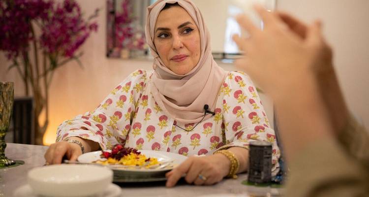 Woman in traditional clothing enjoying a meal at a table.