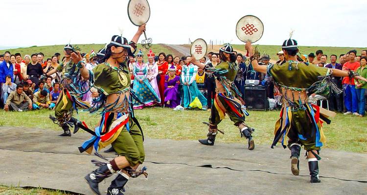 Danseurs mongols traditionnels se produisant en plein air avec une foule décorée qui regarde.
