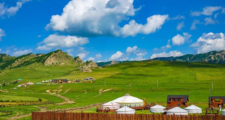De vastes champs verts avec des yourtes traditionnelles et de petites maisons sous un ciel bleu.